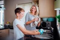 Boy washing dishes with carer - compressed